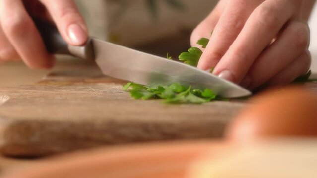 Chopping Fresh Parsley on Wooden Board, Cooking Action. Close-up, shallow dof.