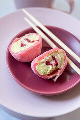 Pink mochi dessert with cream filling and berry. Cut.
