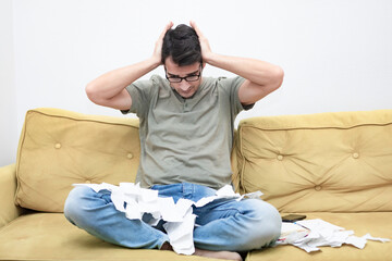 Close up of unhappy man sitting on the couch, stressed and confused by calculate expense from invoice or bills, have no money to pay mortgage or loan. High prices and spending money concept