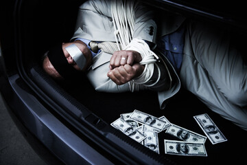 Man, tied up and kidnap in car with money, ransom and crime for wealth, debt or financial negotiation. Person with blindfold, rope and cash in trunk for abduction, danger and risk or scared for life - obrazy, fototapety, plakaty