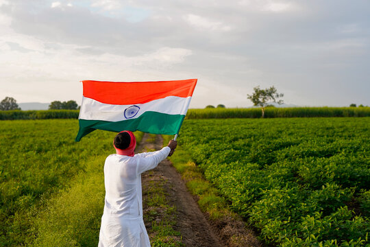 Indian farmer holding indian flag at agriculture field.