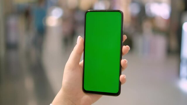 Use green screen for copy space closeup. Chroma key mock-up on smartphone in hand. Woman holds mobile phone and swipes photos or pictures left indoors of cozy home 4K