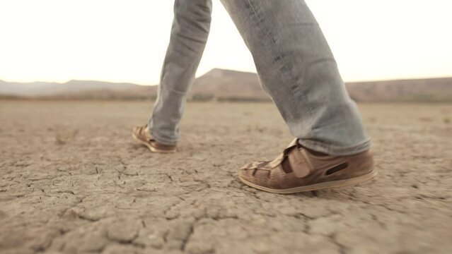 Feet of a man walking through the desert