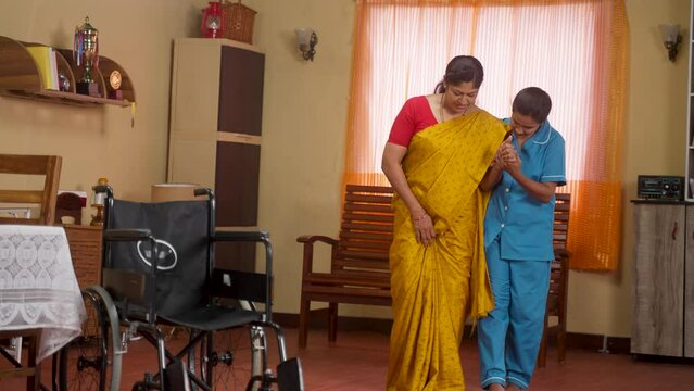 Nurse at home helping injured woman walk at home during therapy session - concept of physiotherapy, mobility exercise and progress