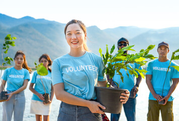 portrait young asian woman in blue volunteer T-shirt holding pot of young sprout plant tree,concept of volunteering,reforestation,conservation of natural resources and the environment - obrazy, fototapety, plakaty