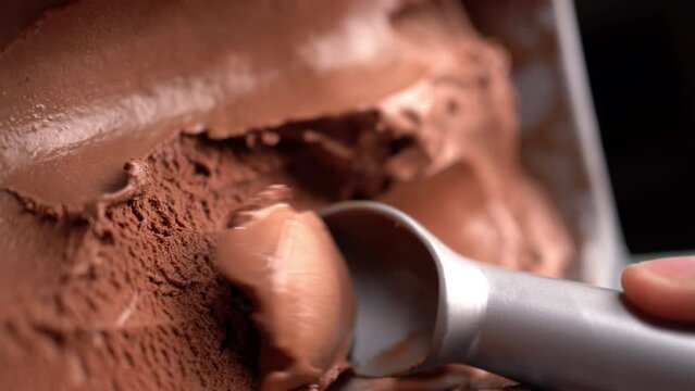 scoop chocolate ice cream with a special spoon and form a ball. Close-up