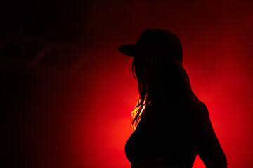 Woman, red light and silhouette at party concert or festival night, stage event or dark. Female person, strobe and glow for artistic creative shadow for dance rave, entertainment or mockup background