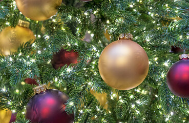 Yellow and burgundy matte Christmas balls on Christmas tree with a garland.