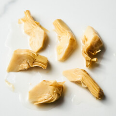 Artichokes in oil on white marble background
