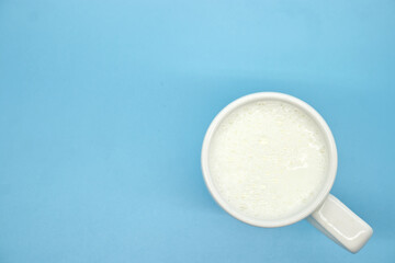 Milk in glass on blue backgroud, top view