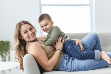 Mature mother with small son on sofa indoors, resting.