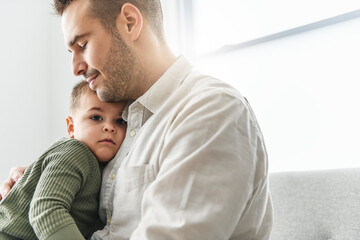 Mature father with small son on sofa indoors, resting.