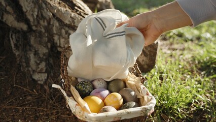 A wicker basket stands by a tree in a sunny forest. I pick up the towel, and there are Easter eggs...