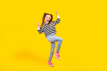 Photo of lucky excited little child dressed striped pullover rising fists empty space isolated...