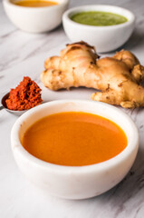 Ginger sauce in a white bowl with a piece of ginger in the background