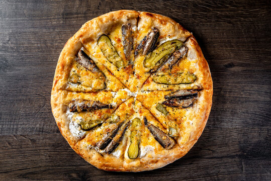 delicious pizza with sprats fish and pickled cucumber on wooden background