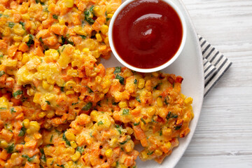 Homemade Carrot Corn Fritters with Ketchup on a Plate, top view. Flat lay, overhead, from above.