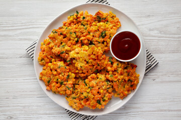 Homemade Carrot Corn Fritters with Ketchup on a Plate, top view. Flat lay, overhead, from above.