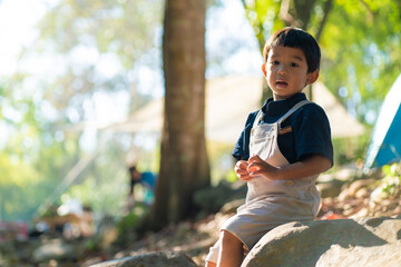 Happy kindergarten 5 year asian boy enjoying outdoor camping in rain forest camp site