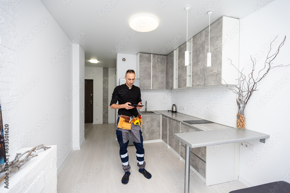 Poster worker with tablet computer checking alarm system indoors