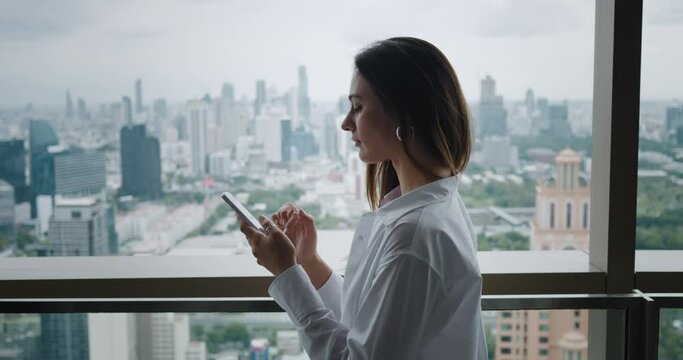 Female in formal suit holding mobile phone job search have business correspondence on city background. female standing on terrace job search on mobile phone or having chat woman want job search