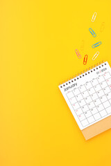 January 2024 desk calendar and paper clips on yellow background.