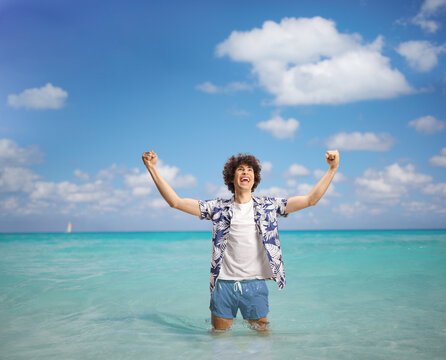Overjoyed young manon a summer holiday gesturing happiness with arms up