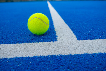 paddle tennis ball at the vertex of the lines of a blue paddle tennis court
