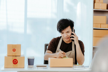 SME small business entrepreneur, young Asian freelancer working at home with boxes Use smartphones and laptops for commercial monitoring, marketing, packaging, online sales.