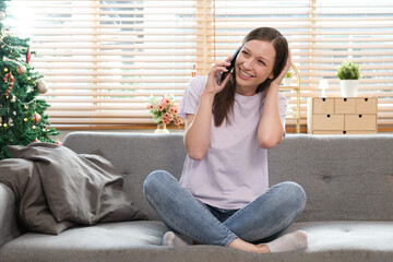 Obraz premium Attractive model sitting on cosy couch in bright living room having a phone call