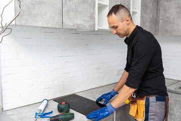 craftsman installs hob in kitchen. Household Appliance Installation Services Concept