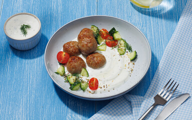 Greek food concept. Greek meatballs (keftedes) with pita bread and tzatziki dip on blue background.