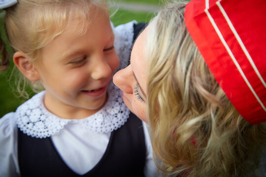 Young and adult schoolgirl on September 1. Generations of schoolchildren of USSR and modern Russia. Female pioneer in red tie and October girl in modern uniform. Mother and daughter having fun