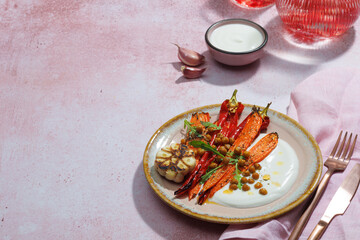 Healthy Homemade Roasted Carrots Ready to Eat with yougurt sause, vegan, vegatarian homemade food on pink backround.