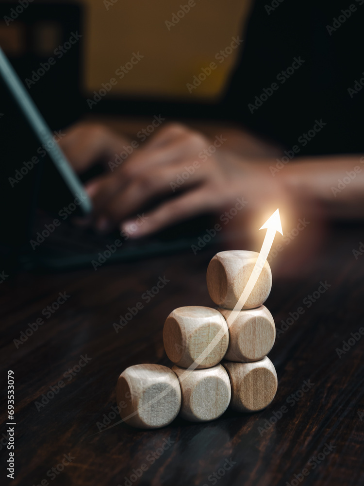Poster rise upward arrow on wooden sticks bar graph chart steps on desk while businessman working with lapt