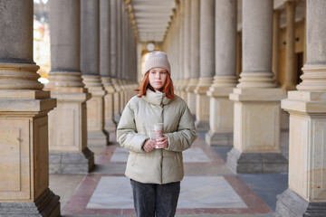 girl with red hair walking at city street in Karlovy Vary