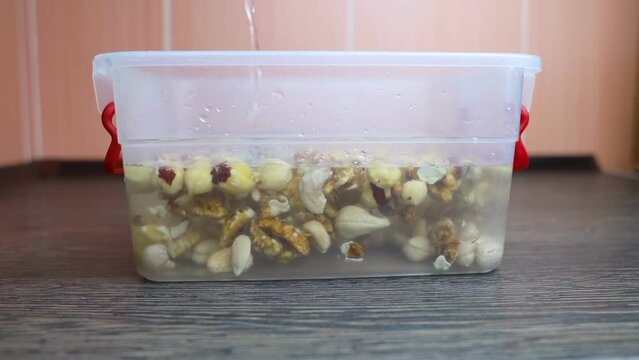 Soaking nuts. Girl shows dirty seeds. Chemical processing of food. Digestive problems are caused by intolerance peanuts, allergies cashews, hazelnuts. Allergic reaction phytic acid. Before and after