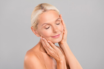 Portrait of smiling peaceful pensioner hand touch skin apply anti wrinkle cream enjoy perfect soft...