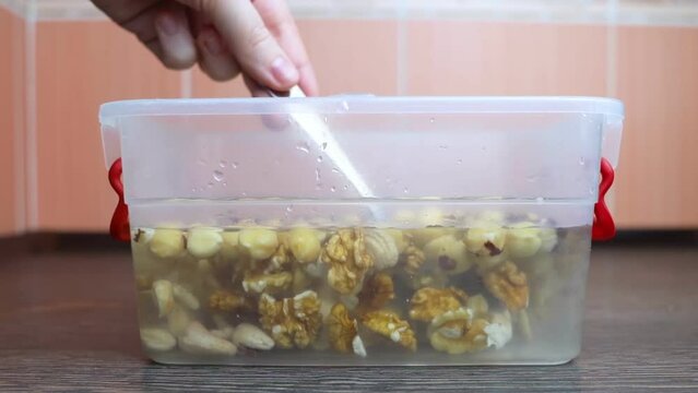 Soaking nuts. Girl shows dirty seeds. Chemical processing of food. Digestive problems are caused by intolerance peanuts, allergies cashews, hazelnuts. Allergic reaction phytic acid. Before and after