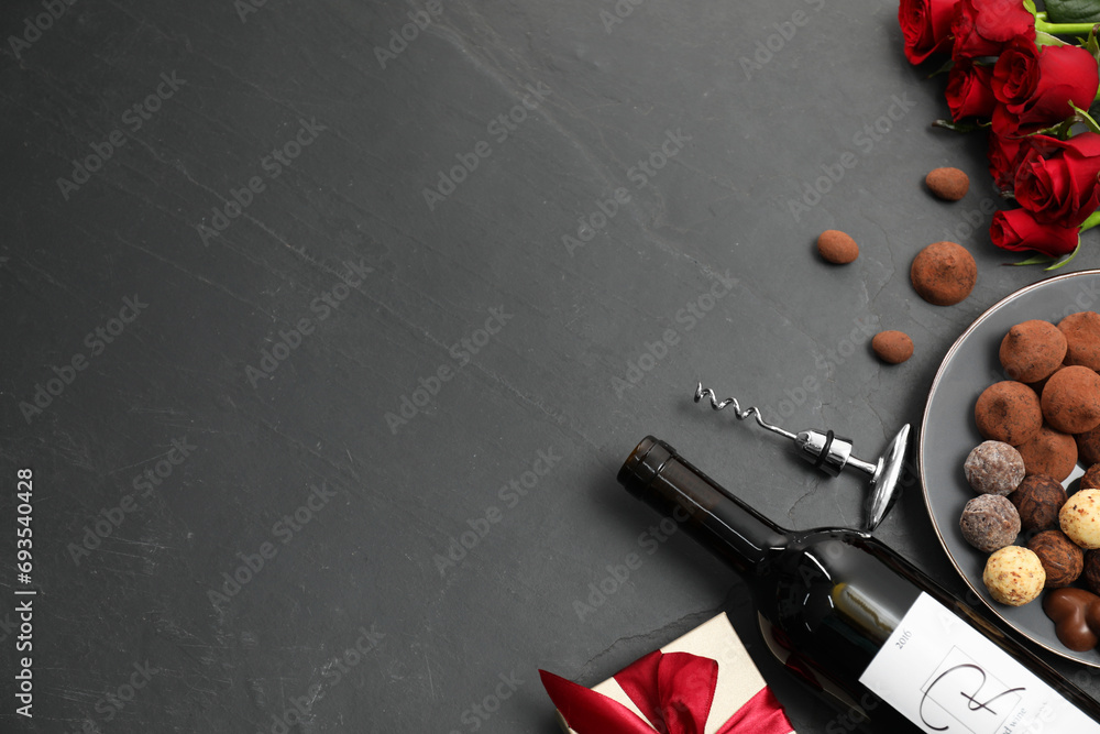 Wall mural Red wine, chocolate truffles, gift box, roses and corkscrew on gray table, flat lay. Space for text