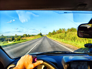 Car salon, steering wheel, hand of woman and view on nature landscape. View from seat of driver on...