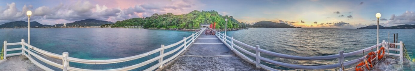 Panoramic picture over a jetty with wooden railing over the tropical sea near Patong on Phuket - obrazy, fototapety, plakaty