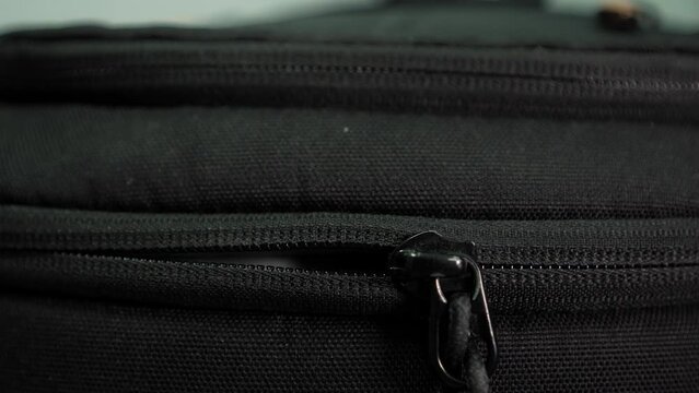Close-up of male hands closing a suitcase and locking it. A man is packing a suitcase in preparation for a trip. A Black Travel Backpack With A Zipper. shot of unzipping and zipping bag.