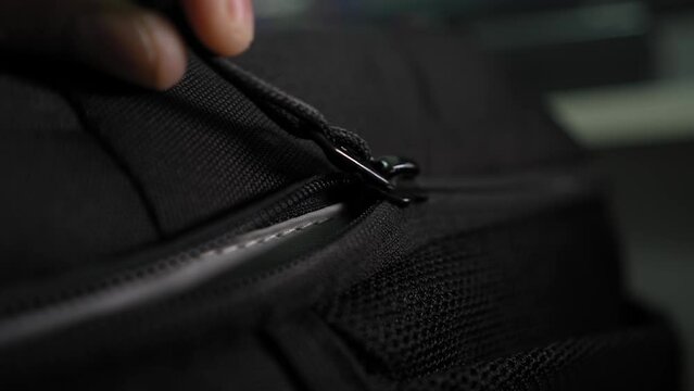 Close-up of male hands closing a suitcase and locking it. A man is packing a suitcase in preparation for a trip. A Black Travel Backpack With A Zipper. shot of unzipping and zipping bag.