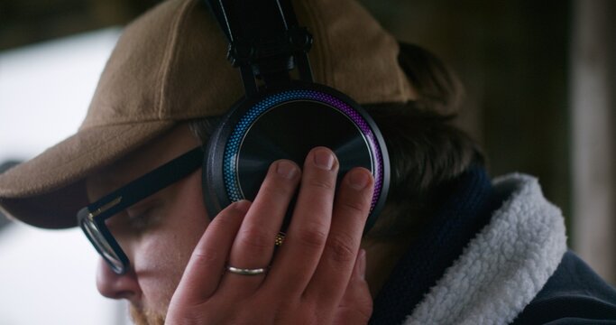 Close up of male musician in glasses and headphones playing MIDI keyboard, composing music and moving rhythmically sitting outdoors. Caucasian man records new song during vacation to mountains.