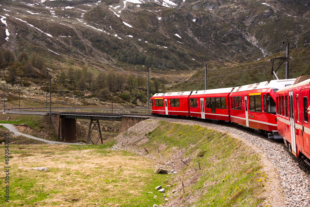 Wall mural red train going in beautiful landscape in switzerland