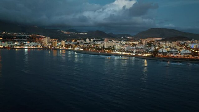 Veduta dal mare della costa di Tenerife al crepuscolo, nubi nel cielo e luci sulla citt&agrave;: Parte 2