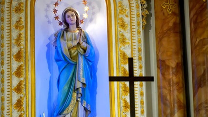 Statue of Virgin Mary in the church and a wooden cross