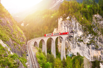 Swiss red train on viaduct in mountain, scenic ride