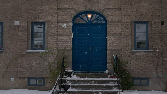 Beautiful entrance to scandinavian style house with wooden door and christmas wreath. Homemade diy xmas decoration. Winter city doors and landscape. Inspiring winter ornaments and nordic lifestyle